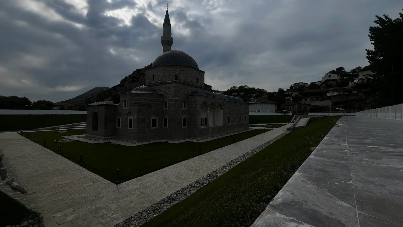 Historic mosque with stone architecture and minaret under cloudy sky